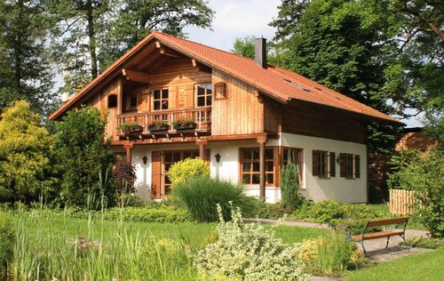 Traditionelles Musterhaus aus Holz mit Mischfassade aus Strukturputz und Lärchenholz