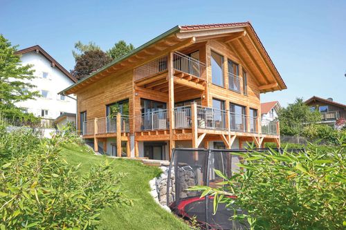 Modernes Holzhaus im Landhausstil mit Holzfassade, Holz-Alu-Fenstern und großzügigen Balkonen