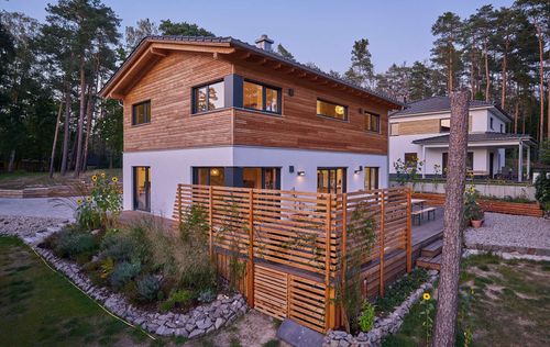 Modernes Holzhaus im voralpenstil mit Mischfassade aus Lärchenholz und mineralischem Putz, Anbau mit Flachdach