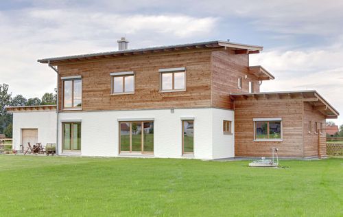 Modernes Holzhaus mit Pultdach, gemischte Fassade aus mineralischem Putz und Lärchenholz