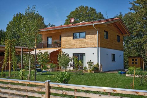 Modernes Holzhaus im Landhausstil mit flachem Satteldach und gemischter Fassade aus Lärchenholz und mineralischem Außenputz