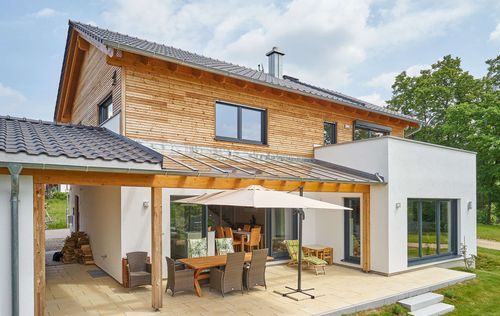 Modernes Holzhaus im Landhausstil mit Mischfassade aus Fichtenholz und mineralischem Außenputz
