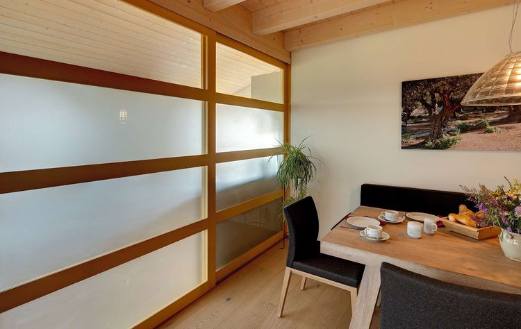 Das Holz-Glas-Schiebeelement des modernen Holzhauses im Landhausstil auf einem Hanggrundstück