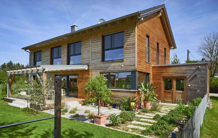 Modernes Holzhaus im Landhausstil mit Holzfassade aus Lärchenholzbohlen und Doppelcarport