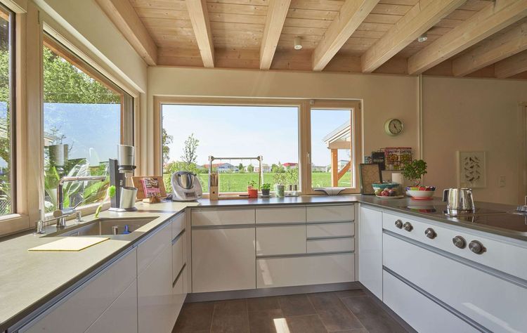 Die Küche des modernen Holzhauses im Landhausstil mit Holzfassade aus Lärchenholzbohlen und Doppelcarport