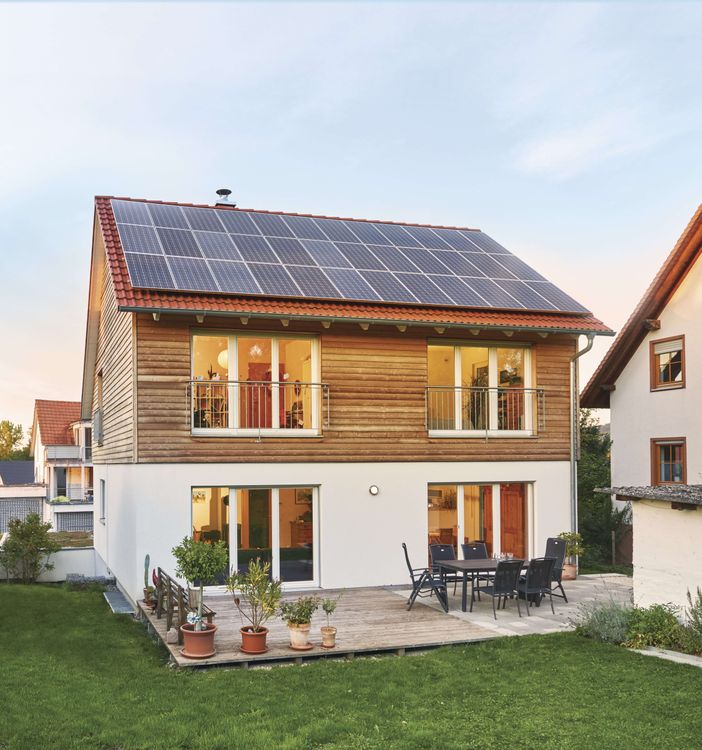 Plusenergiehaus mit Terrasse, Solarpanels auf dem Dach und Holzverschalung