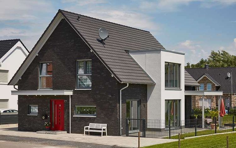 Der Hausentwurf Gersbach hat eine grau-schwarze Klinkerfassade und eine besonders hervorstechende rote Haustüre.