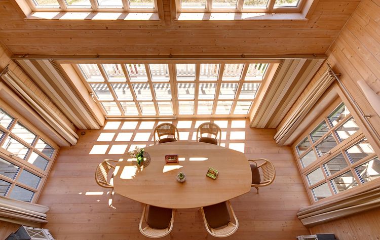Der Essbereich samt Galerie des Holzhauses im Landhausstil mit Holzfassade und mehrere Balkonen, drei Giebeln und vielen Fenstern