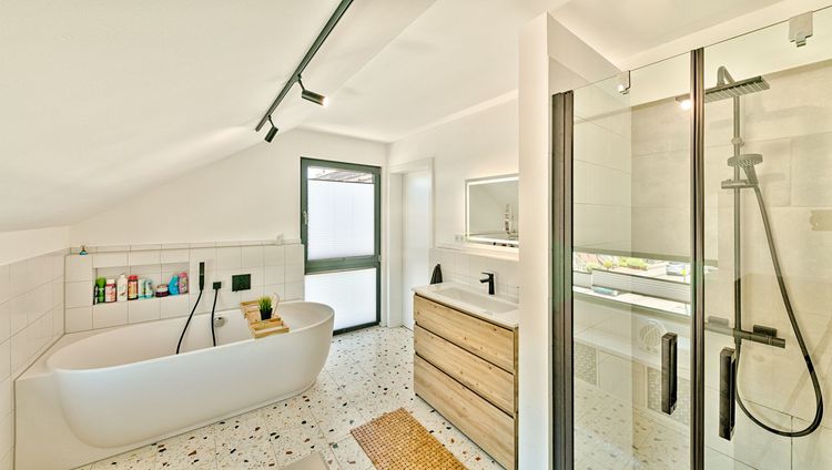 Helles Badezimmer mit Badewanne und verglaster Dusche
