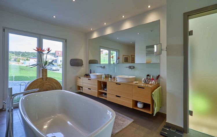 Das Badezimmer des modernen Bungalows aus Holz im Bauhausstil mit mineralischem Außenputz mit freistehender Badewanne