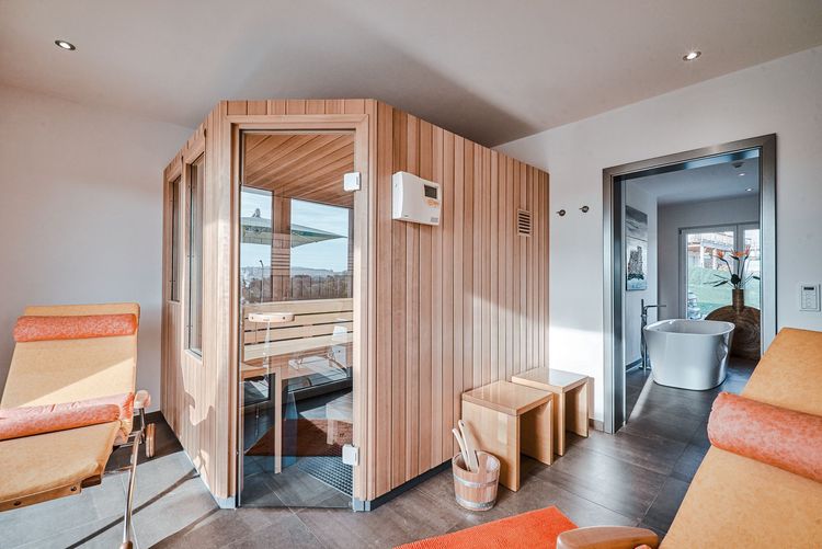 Die Sauna des modernen Bungalows aus Holz im Bauhausstil mit mineralischem Außenputz mit Pool