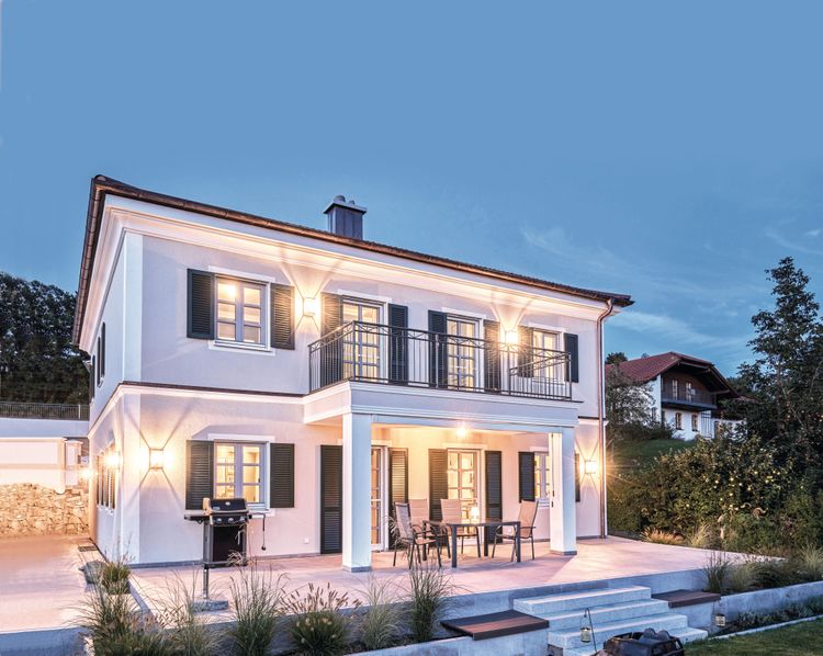 Modernes, mediterranes Holzhaus im Stil einer Stadtvilla mit weißem, mineralischem Außenputz und grünen Fensterläden