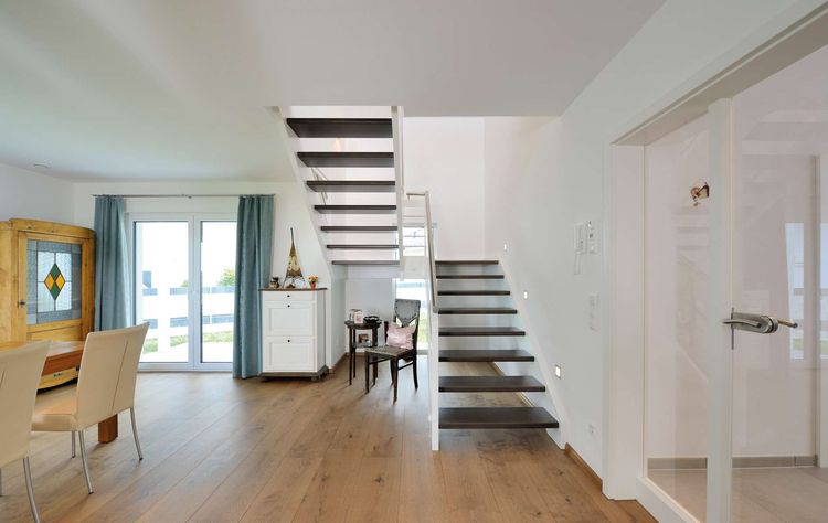Die dunklen Holzstufen stellen bei dieser Podesttreppe aus Nussbaum einen harmonischen Kontrast zur weiß lackierten Konstruktion dar