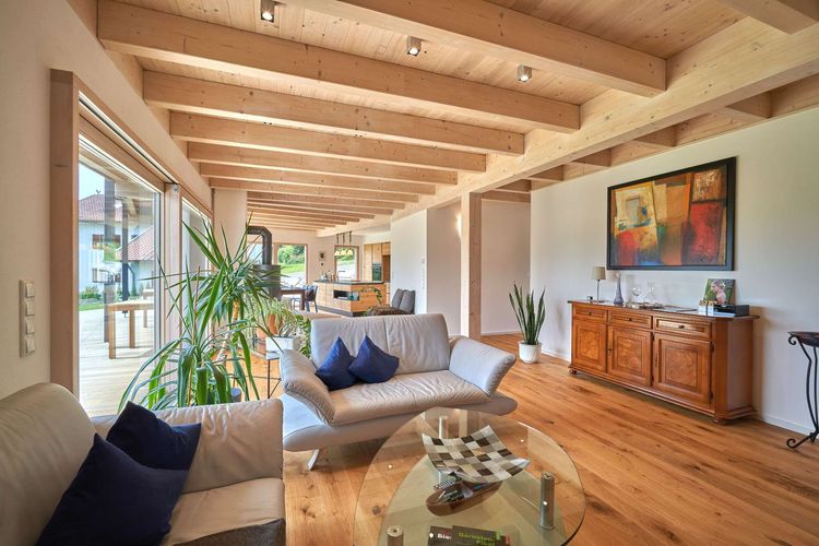 Das Wohnzimmer des modernen Holzhauses mit Pultdach und Mischfassade aus mineralischem Außenputz und Lärchenholz, ein Knick im Grundriss sorgt für den perfekten Ausblick