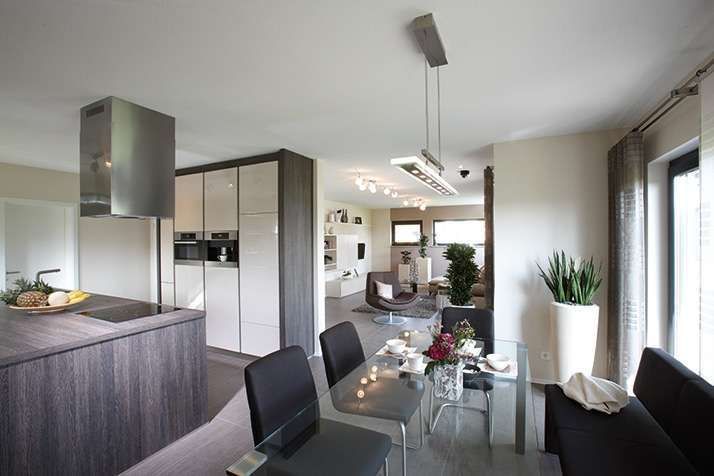 Wohnküche mit Kücheninsel in verwitterter Holzoptik und Essbereich mit Glastisch