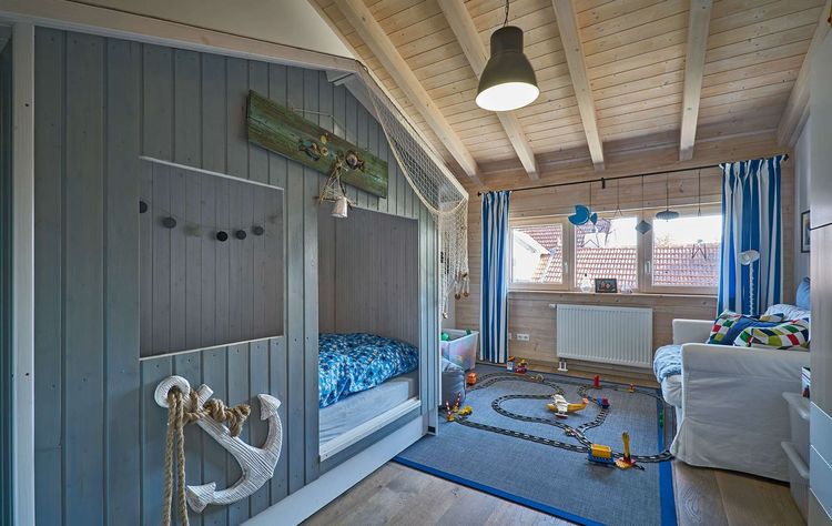Das Kinderzimmer des modernen Holzhauses im Landhausstil mit Mischfassade aus mineralischem Putz und Holz