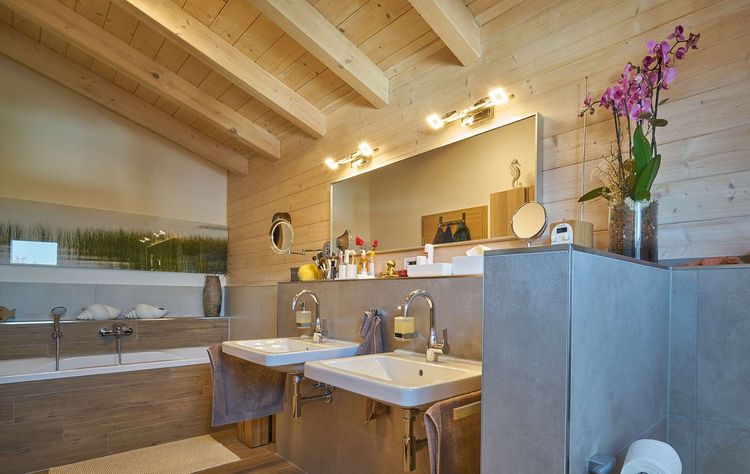 Das Badezimmer des modernen Holzhauses im Landhausstil mit Mischfassade aus mineralischem Putz und Holz