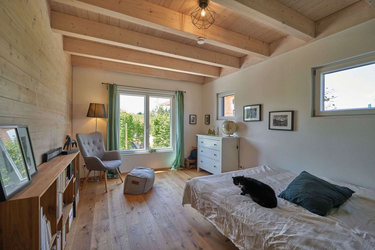 Das Schlafzimmer des modernen Holzhauses im Landhausstil mit durchgängiger Lärchenholzfassade und Holz-Alu-Fenstern