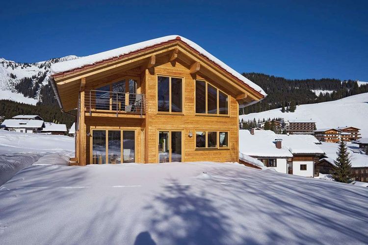 Verschneites Alpenhaus mit Satteldach und Schneefangsystem