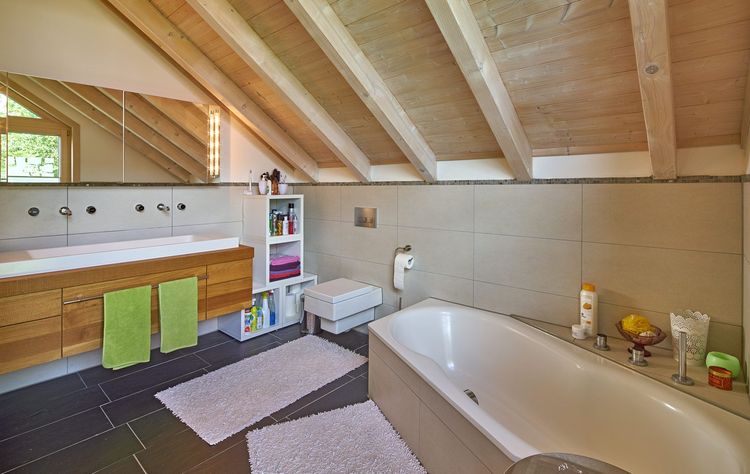 Das Badezimmer des Holzhauses im Landhausstil mit Lärchenfassade, großer Glasfront und moderne Technik mit Eckbadewanne