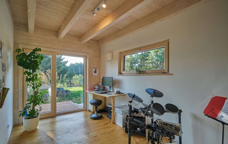 Das Büro des modernen Holzhauses im voralpenstil mit Mischfassade aus Lärchenholz und mineralischem Putz, Anbau mit Flachdach