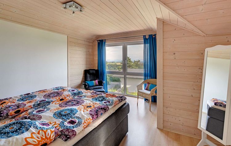 Das Schlafzimmer des Holzhauses im Landhausstil mit gemischter Fassade aus mineralischem Putz und Holz