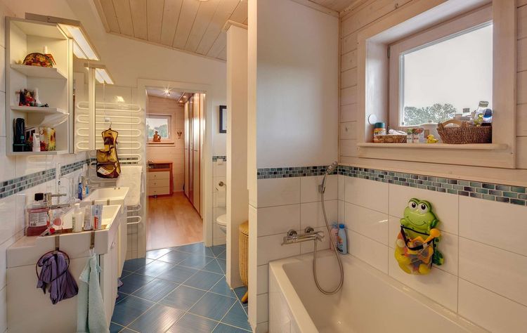 Das Badezimmer des modernen Holzhauses mit Pultdach und gemischter Fassade aus mineralischem Putz und Lärchenholz