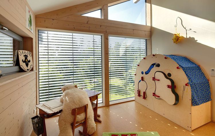 Das Kinderzimmer des Holzhauses im Landhausstil mit durchgängiger Holzfassade und großer Glasfront