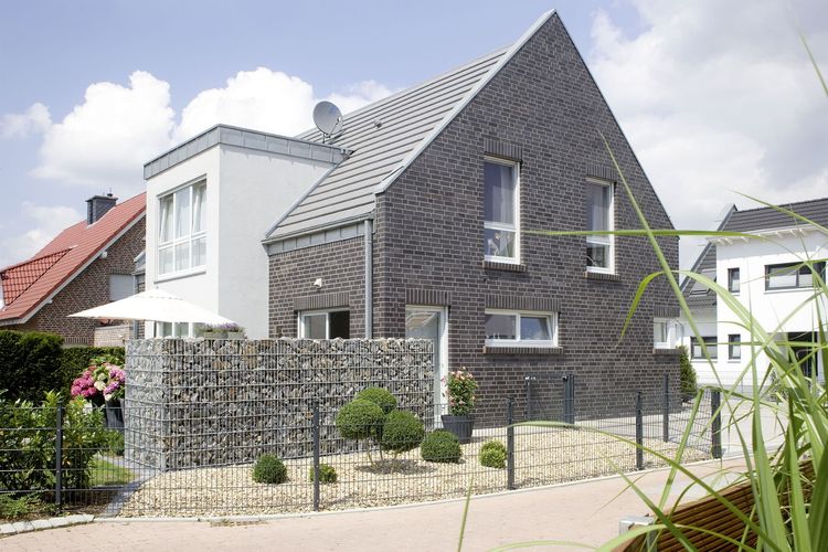 Einfamilienhaus mit Satteldach, Zwerchhaus und Gabionen als Sichtschutz für den Garten