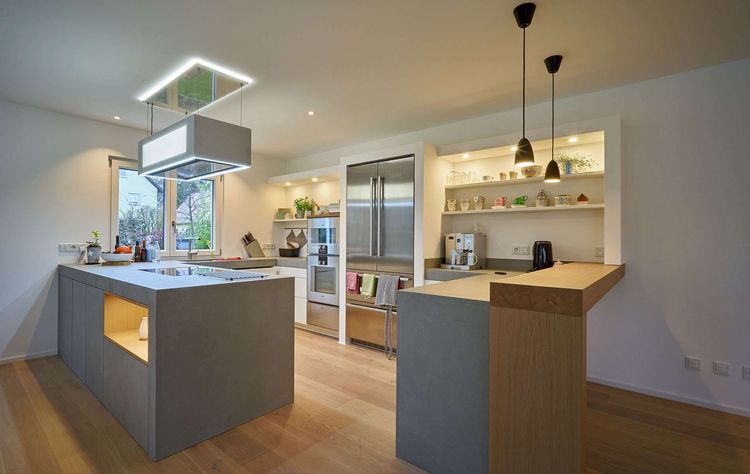 Eine Küche des modernen Wohnungsbaus aus Holz mit Mischfassade aus Außenputz und Holz und Flachdach auf drei Ebenen