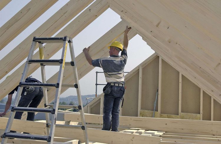 Bauarbeiter bei der Konstruktion von lastabtragenden Balken für den Dachstuhl