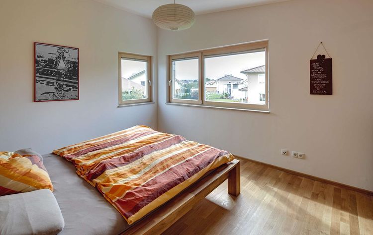 Das Schlafzimmer des modernen Holzhauses mit Pultdach, Putzfassade und Schiebeläden aus Lärche