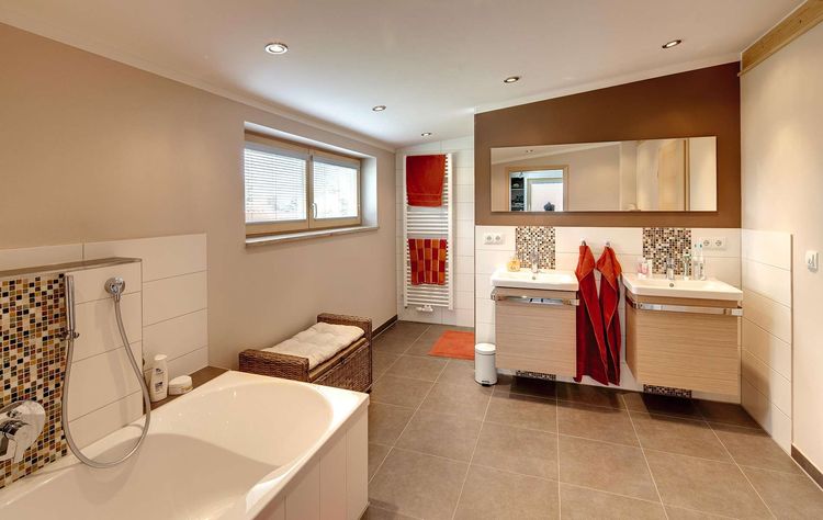 Das Badezimmer des modernen Holzhauses mit Pultdach, Putzfassade und Schiebeläden aus Lärche
