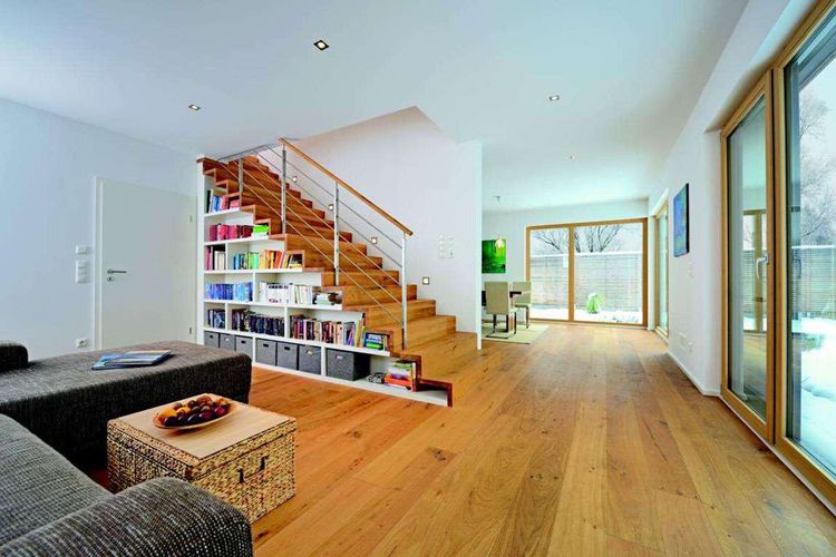 Offenes Wohnzimmer mit Holzparkett und Holztreppe mit eingebautem Bücherregal