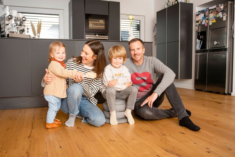 Glückliche Familie im Wohnzimmer ihres neuen FingerHaus-Einfamilienhauses