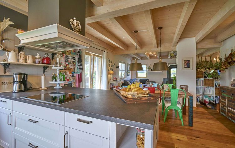 Die Küche des traditionellen Holzhauses mit Mischfassade aus Lärchenholz und Putz, mit flachem Satteldach und hohem Kniestock