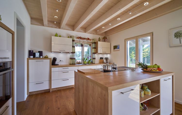Die Küche des modernen Holzhauses im Stadtvilla-Stil mit mineralischem Außenputz und teilweise überdachter Terrasse