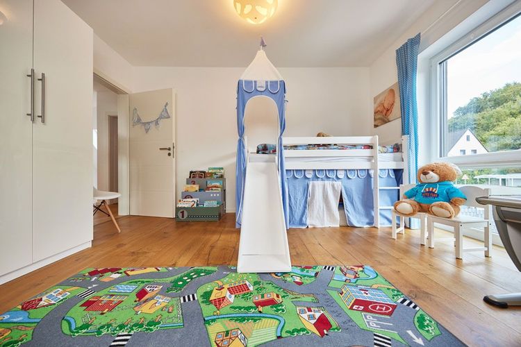 Kinderzimmer mit großen Fenstern und blauem Kinderbett