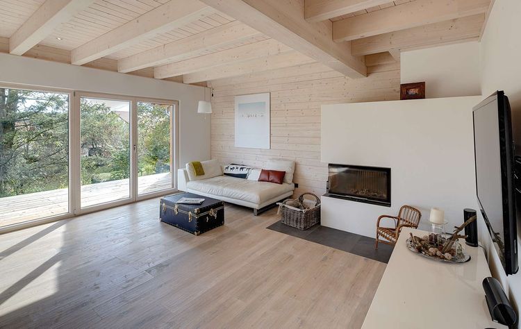 Das Wohnzimmer des modernen Holzhauses im Landhausstil mit durchgängiger Holzfassade