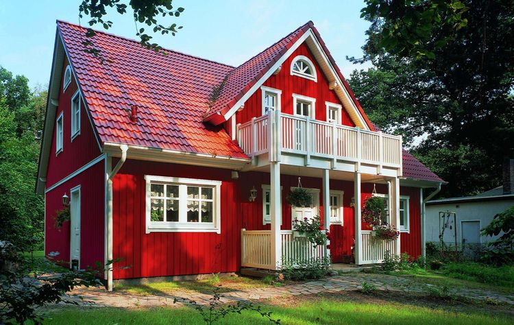 Rotes Fertighaus im skandinavischen Stil mit Holzverschalung und Veranda