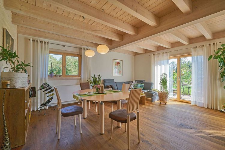Das Esszimmer des modernen Holzhauses im Landhausstil mit flachem Satteldach und gemischter Fassade aus Lärchenholz und mineralischem Außenputz