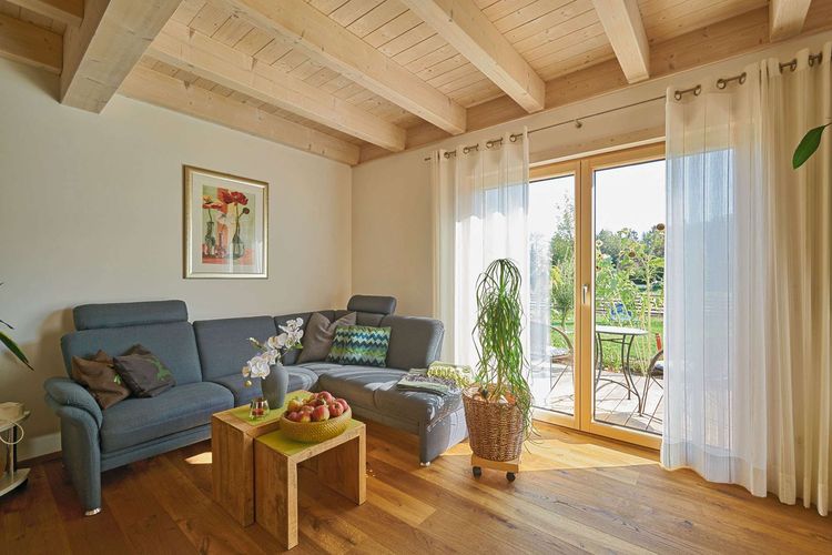 Das Wohnzimmer des modernen Holzhauses im Landhausstil mit flachem Satteldach und gemischter Fassade aus Lärchenholz und mineralischem Außenputz
