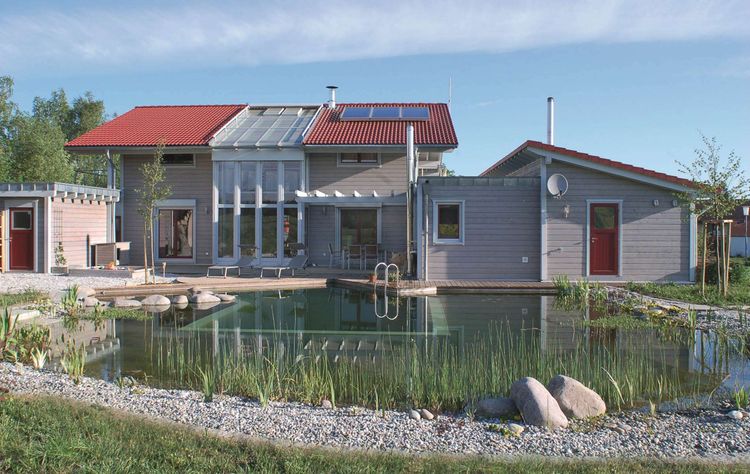 Modernes Ökohaus mit grauer Holzfassade und Gartenteich