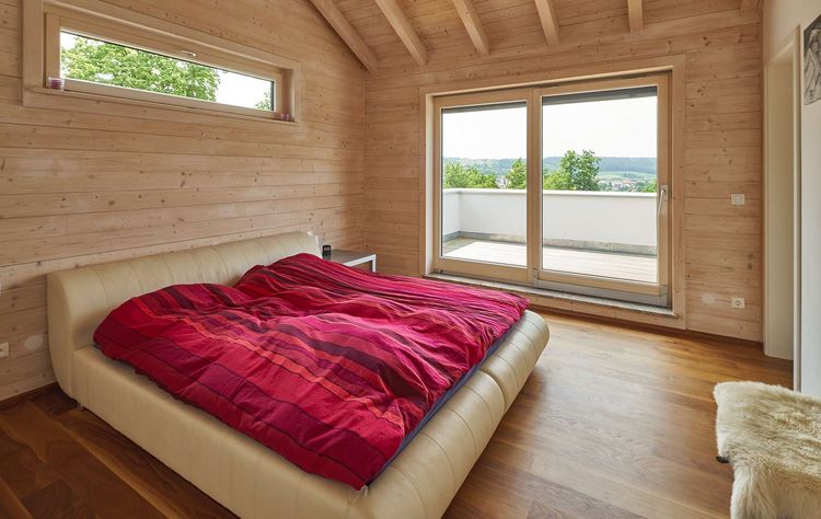 Das Schlafzimmer des modernen Holzhauses im Landhausstil mit Mischfassade aus Fichtenholz und mineralischem Außenputz