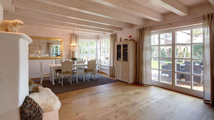 Der Wohn- und Essbereich des traditionellen Holzhauses mit durchgängiger, grauer Holzfassade, inspiriert von unserem Musterhaus 'St. Johann'