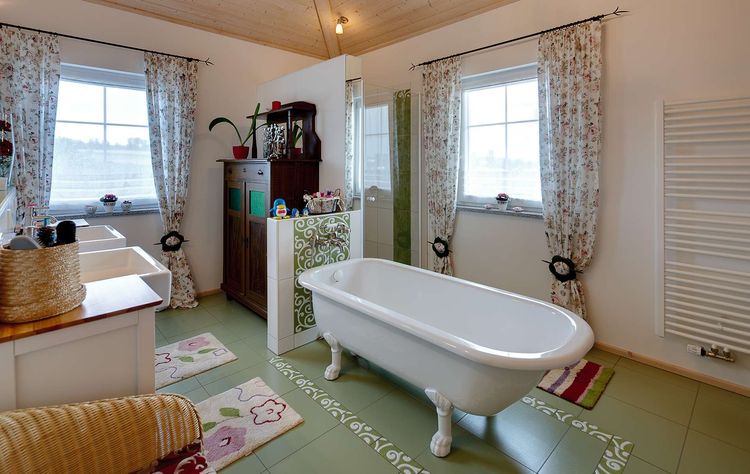 Das Badezimmer des modernen Holzhauses in mediterranem Stil mit mineralischem Außenputz mit freistehender Badewanne