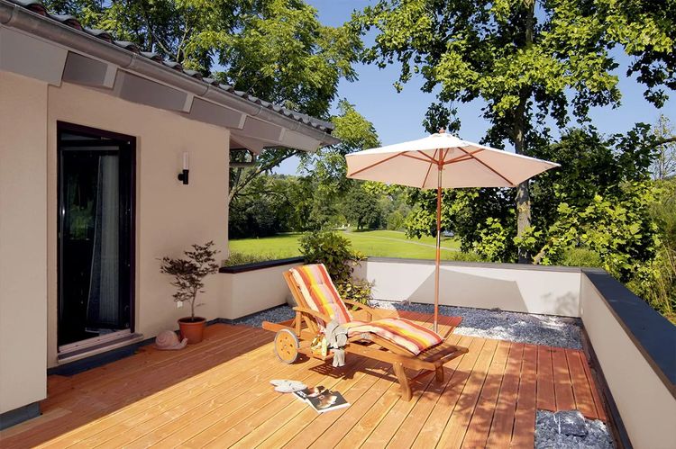 Gemütliche Dachterrasse mit Holzparkett, Sonnenschirm und Liegestuhl