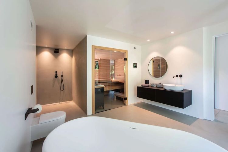 Modernes Badezimmer mit offener Dusche, freistehender Badewanne und Indoorsauna