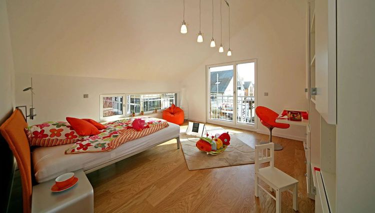 Schlafzimmer mit Holzparkett und großen Fenstern