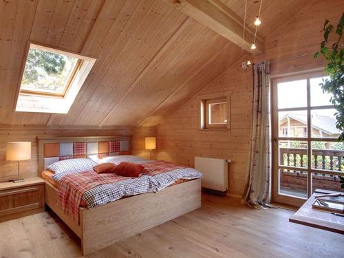 Das Schlafzimmer des traditionellen Musterhauses aus Holz mit Mischfassade aus Strukturputz und Lärchenholz
